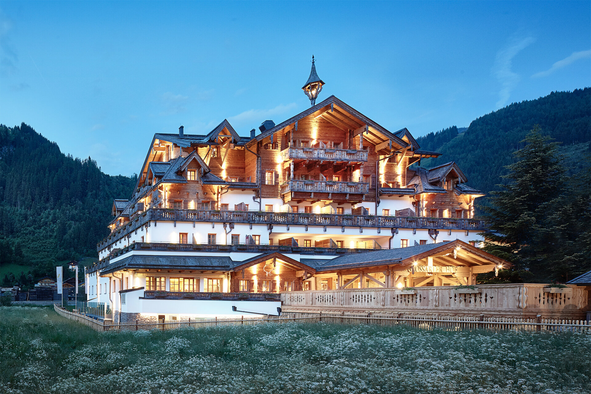 Außenansicht des Boutique Hotel Salzburg bei Abenddämmerung, beleuchtet und umgeben von idyllischer Berglandschaft | © Michael Huber I www.huber-fotografie.at