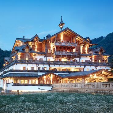 Außenansicht des Boutique Hotel Salzburg bei Abenddämmerung, beleuchtet und umgeben von idyllischer Berglandschaft | © Michael Huber I www.huber-fotografie.at