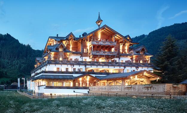 Außenansicht des Boutique Hotel Salzburg bei Abenddämmerung, beleuchtet und umgeben von idyllischer Berglandschaft | © Michael Huber I www.huber-fotografie.at