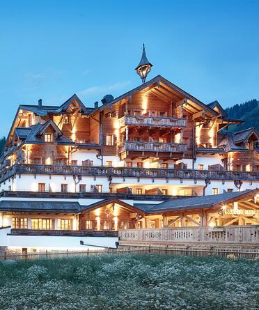 Außenansicht des Boutique Hotel Salzburg bei Abenddämmerung, beleuchtet und umgeben von idyllischer Berglandschaft | © Michael Huber I www.huber-fotografie.at
