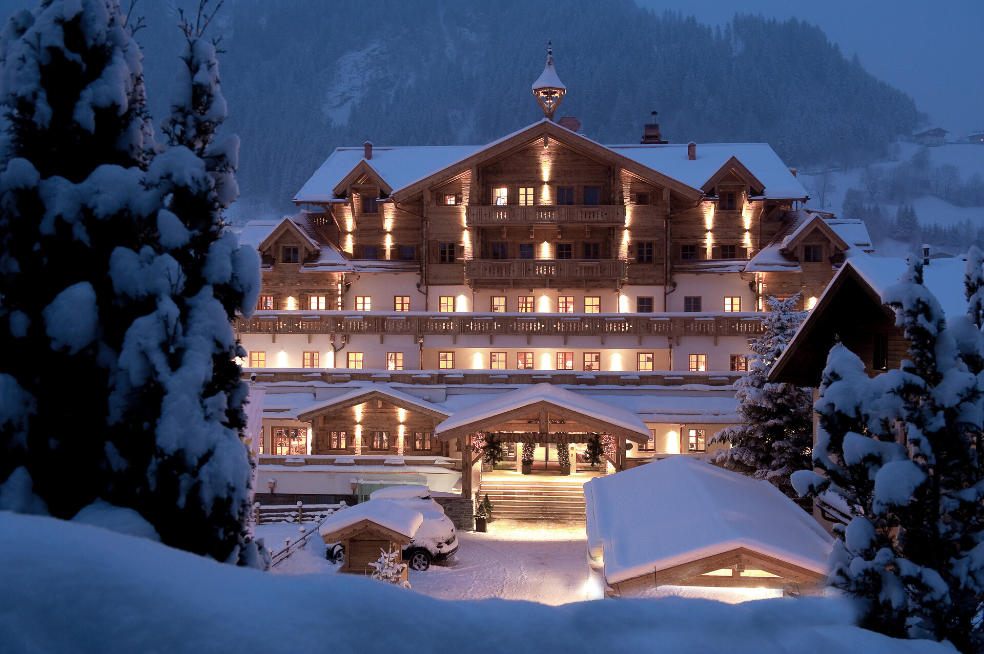Winterliche Außenansicht des Boutique Hotel Salzburg bei Nacht, stimmungsvoll beleuchtet und umgeben von verschneiter Berglandschaft | © Michael Huber I www.huber-fotografie.at