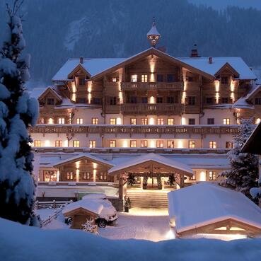 Winterliche Außenansicht des Boutique Hotel Salzburg bei Nacht, stimmungsvoll beleuchtet und umgeben von verschneiter Berglandschaft | © Michael Huber I www.huber-fotografie.at