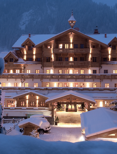 Winterliche Außenansicht des Boutique Hotel Salzburg bei Nacht, stimmungsvoll beleuchtet und umgeben von verschneiter Berglandschaft | ©  Gruber Michael
