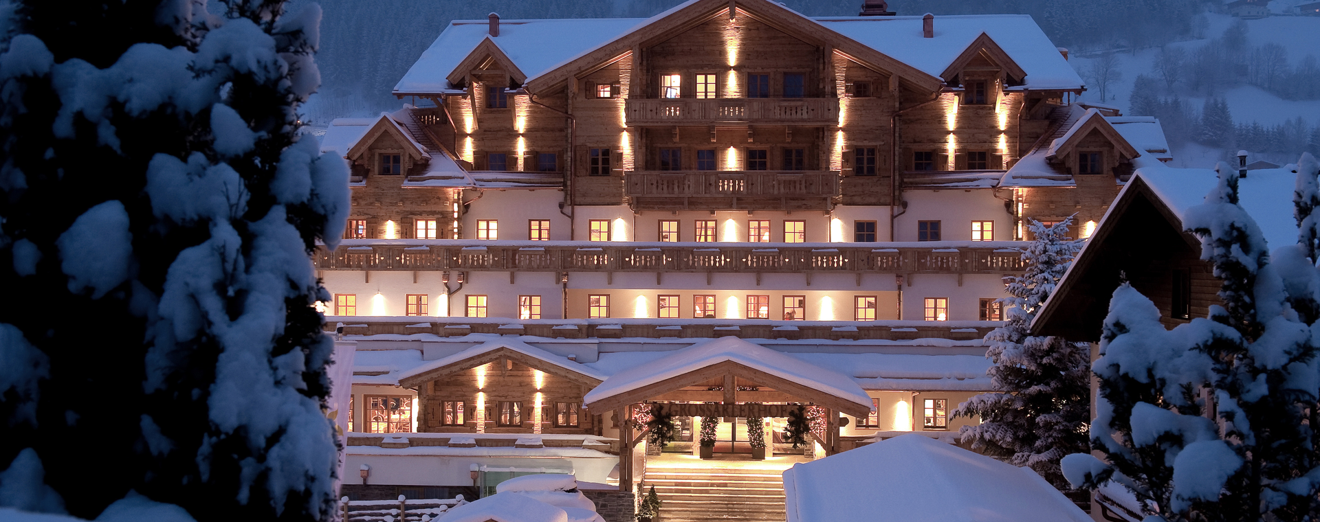 Winterliche Außenansicht des Boutique Hotel Salzburg bei Nacht, stimmungsvoll beleuchtet und umgeben von verschneiter Berglandschaft | ©  Gruber Michael