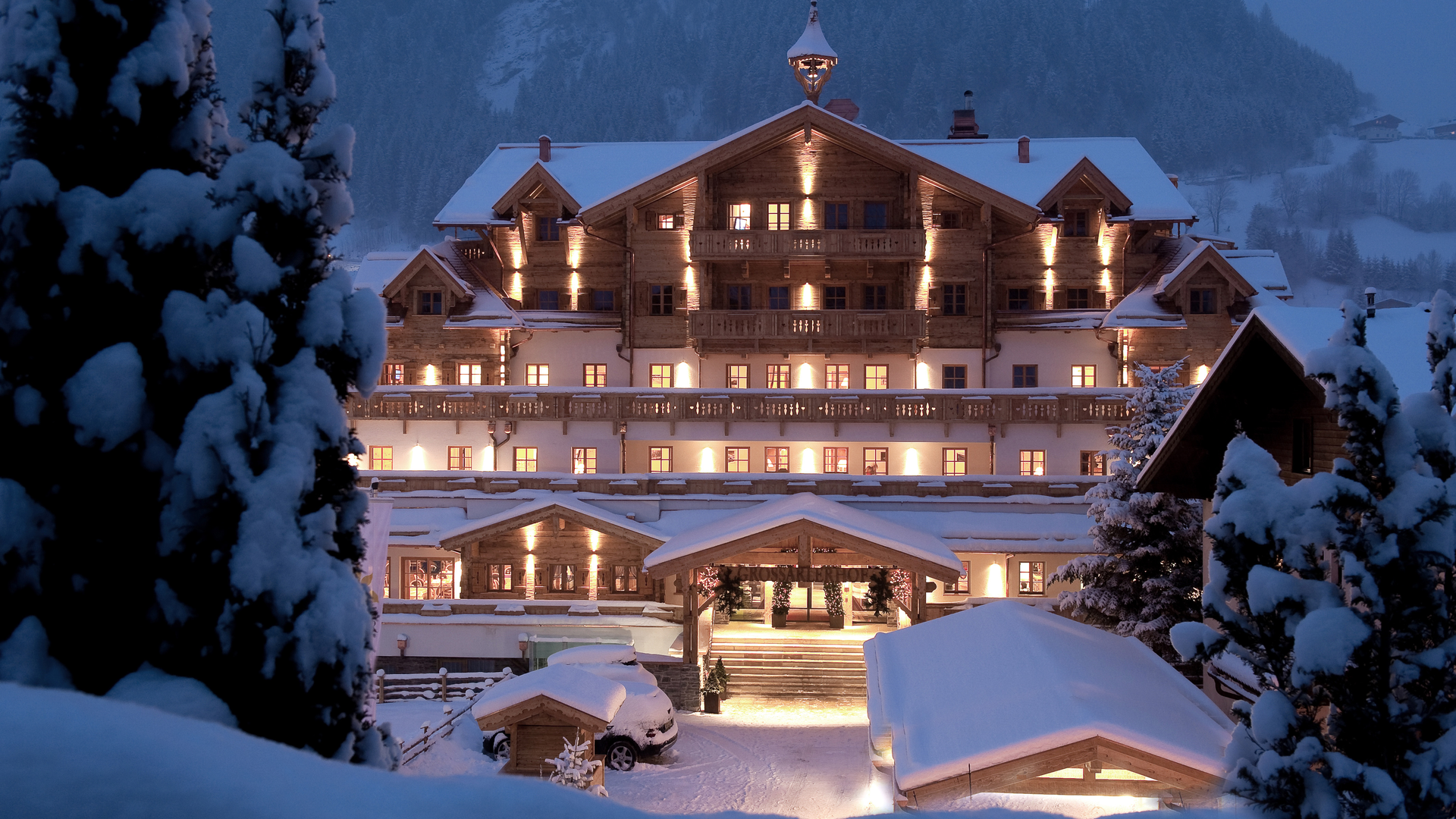 Winterliche Außenansicht des Boutique Hotel Salzburg bei Nacht, stimmungsvoll beleuchtet und umgeben von verschneiter Berglandschaft | ©  Gruber Michael