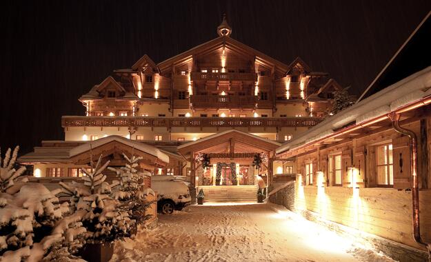 Grossarler Hof bei Nacht, beleuchtet mit verschneitem Eingangsbereich und traditionellen Holzelementen in winterlicher Atmosphäre | © Michael Gruber