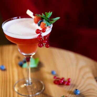 Fruchtiger Cocktail im Boutique Hotel Salzburg, dekoriert mit Johannisbeeren, Minze und Beeren, serviert in stilvollem Ambiente | © www.fabianfranzferdinand.com