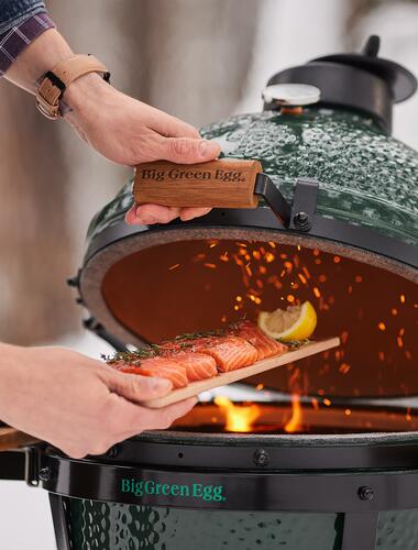 Saftig frischer Lachs auf einem Holzbrett wird in einem Big Green Egg Grill zubereitet