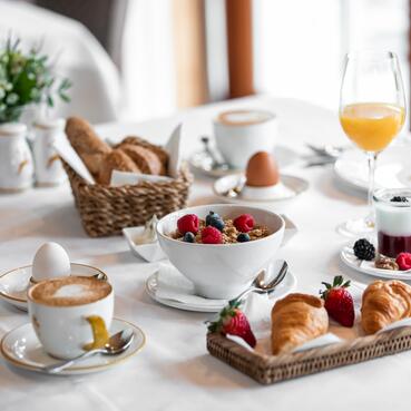 Reichhaltiges Frühstück im Boutique Hotel Salzburg mit Croissants, frischem Obst, Joghurt, Müsli und Heißgetränken auf stilvoll gedecktem Tisch