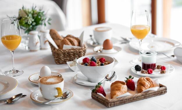 Reichhaltiges Frühstück im Boutique Hotel Salzburg mit Croissants, frischem Obst, Joghurt, Müsli und Heißgetränken auf stilvoll gedecktem Tisch