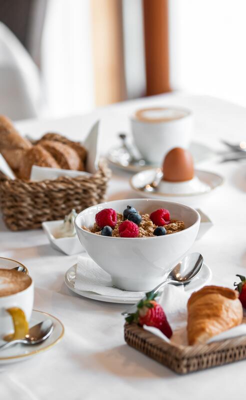 Reichhaltiges Frühstück im Boutique Hotel Salzburg mit Croissants, frischem Obst, Joghurt, Müsli und Heißgetränken auf stilvoll gedecktem Tisch
