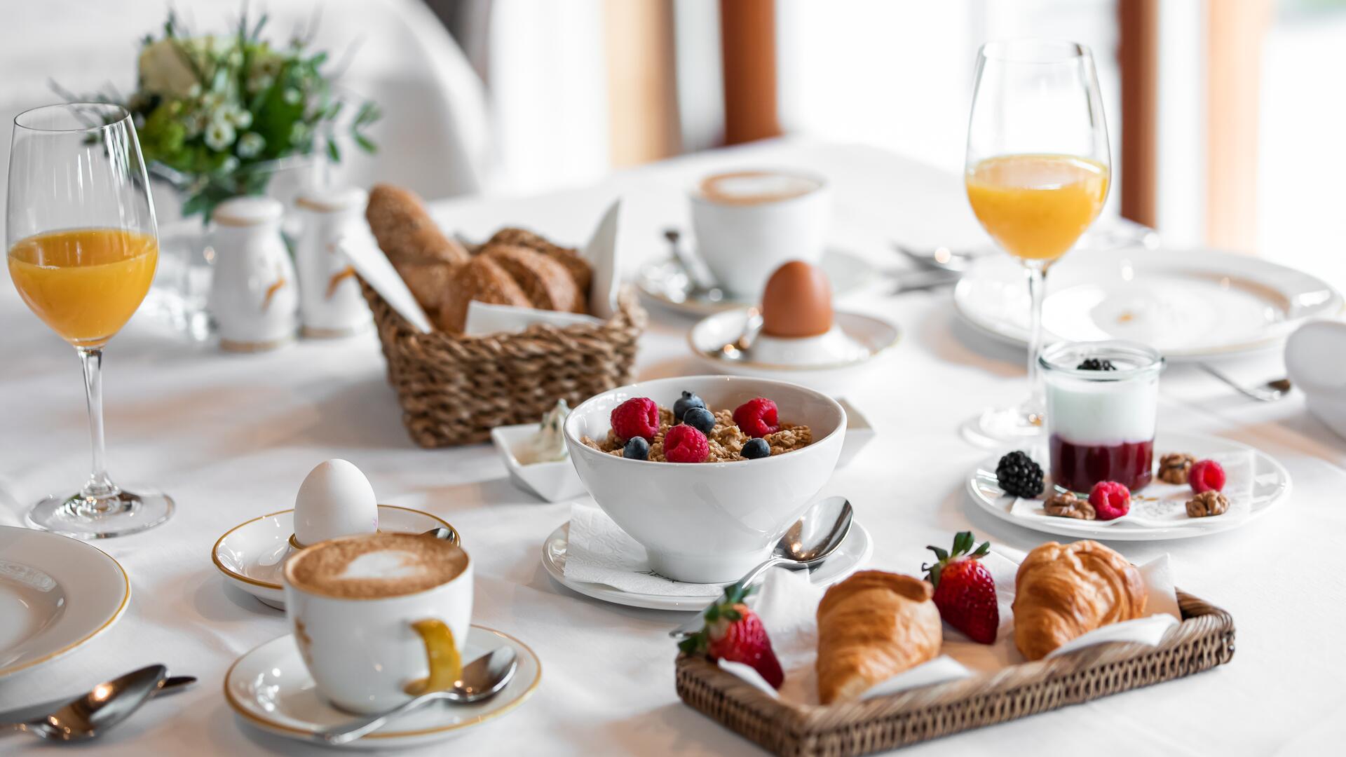 Reichhaltiges Frühstück im Boutique Hotel Salzburg mit Croissants, frischem Obst, Joghurt, Müsli und Heißgetränken auf stilvoll gedecktem Tisch