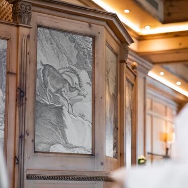 Detailansicht eines kunstvoll gestalteten Holzmöbels mit Wildtiermotiv im Boutique Hotel Salzburg, kombiniert mit elegantem Ambiente