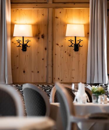 Gemütliches Restaurant mit Holzwänden, stilvollen Wandlampen und elegant gedeckten Tischen