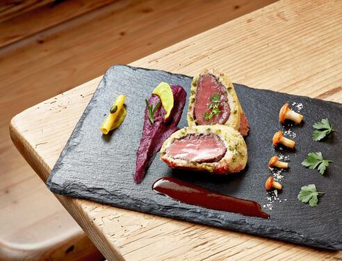 Gourmetgericht im Boutique Hotel Salzburg: Perfekt angerichtetes Fleisch im Teigmantel mit Beilagen und feiner Sauce auf einer Schieferplatte | © Michael Huber I www.huber-fotografie.at