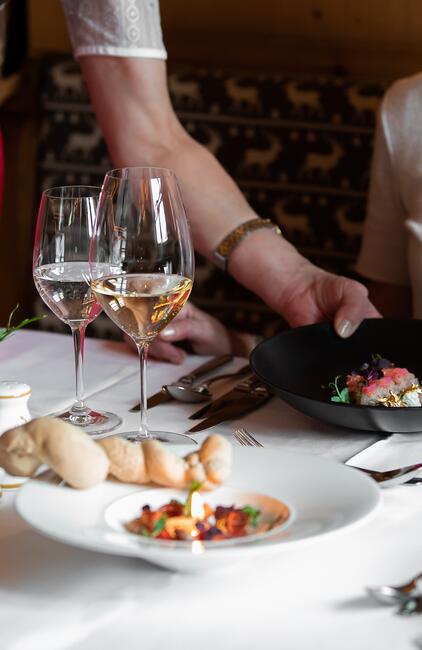 Elegantes Dinner mit liebevoll angerichteten Gerichten, serviert mit zwei Gläsern Weißwein in stilvoller Atmosphär
