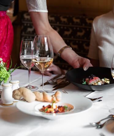 Elegantes Dinner mit liebevoll angerichteten Gerichten, serviert mit zwei Gläsern Weißwein in stilvoller Atmosphär
