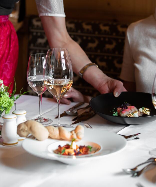 Elegantes Dinner mit liebevoll angerichteten Gerichten, serviert mit zwei Gläsern Weißwein in stilvoller Atmosphär | © SPORTALPEN