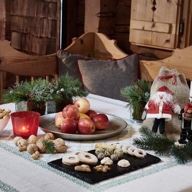 Weihnachten im Salzburger Land – festlich dekorierter Tisch mit Äpfeln, Nüssen, Keksen, Kerze und weihnachtlicher Dekoration in gemütlicher Holzhütte | © Michael Huber I www.huber-fotografie.at