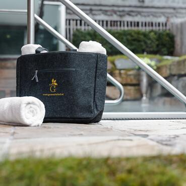 Schwarze Tasche mit Handtüchern, ein Handtuch liegt auf dem Boden. Perfekt für eine Auszeit im Salzburger Land.