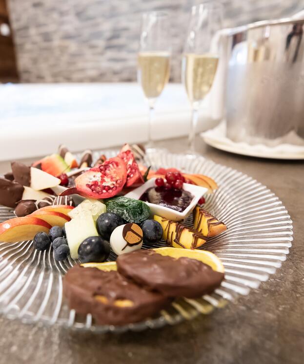 Ein Glas Champagner und ein Teller mit Früchten und Schokolade, eine genussvolle Auszeit im Salzburger Land.