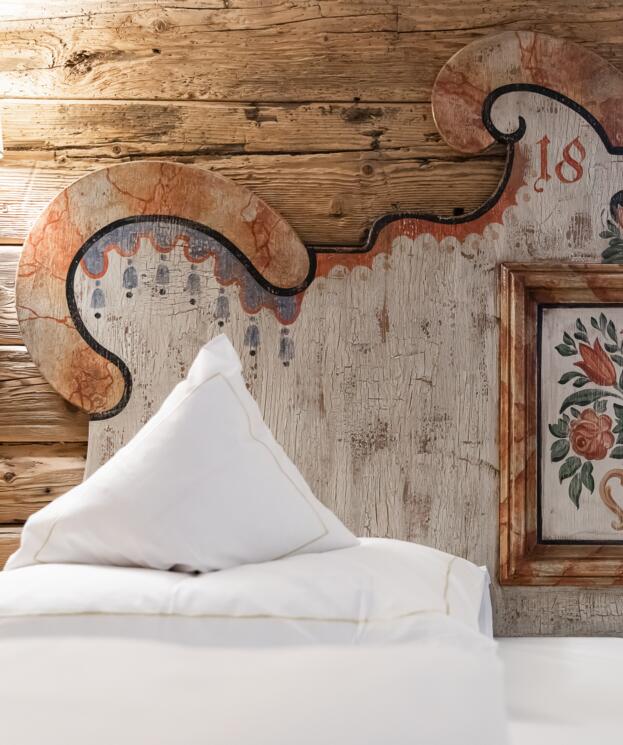 Detail eines kunstvoll bemalten Kopfteils im Boutique Hotel, mit rustikaler Holzverkleidung und traditionellem Design für eine gemütliche Atmosphäre