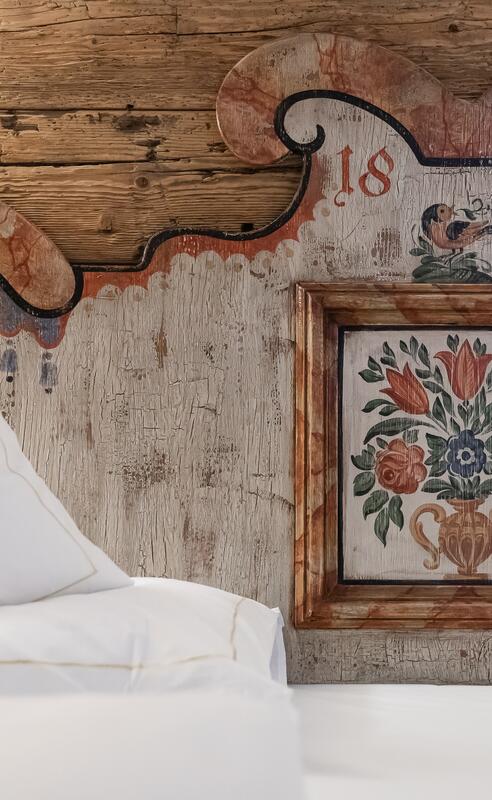 Detail eines kunstvoll bemalten Kopfteils im Boutique Hotel, mit rustikaler Holzverkleidung und traditionellem Design für eine gemütliche Atmosphäre