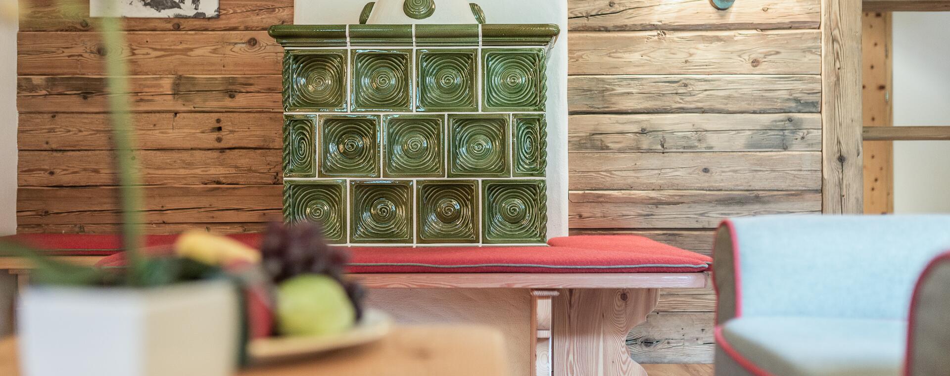 Traditioneller grüner Kachelofen mit Sitzbank im Boutique Hotel Salzburg, ergänzt durch rustikale Holzelemente und gemütliches Ambiente