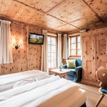 Gemütliches Zimmer im Boutique Hotel Salzburg mit Holzwänden, traditionellen Möbeln, Balkonblick und einladendem Ambiente