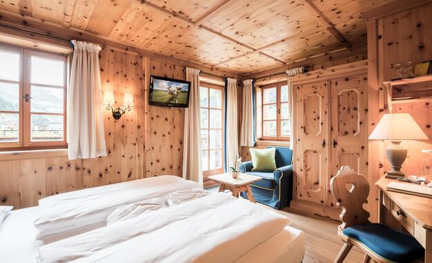 Gemütliches Zimmer im Boutique Hotel Salzburg mit Holzwänden, traditionellen Möbeln, Balkonblick und einladendem Ambiente