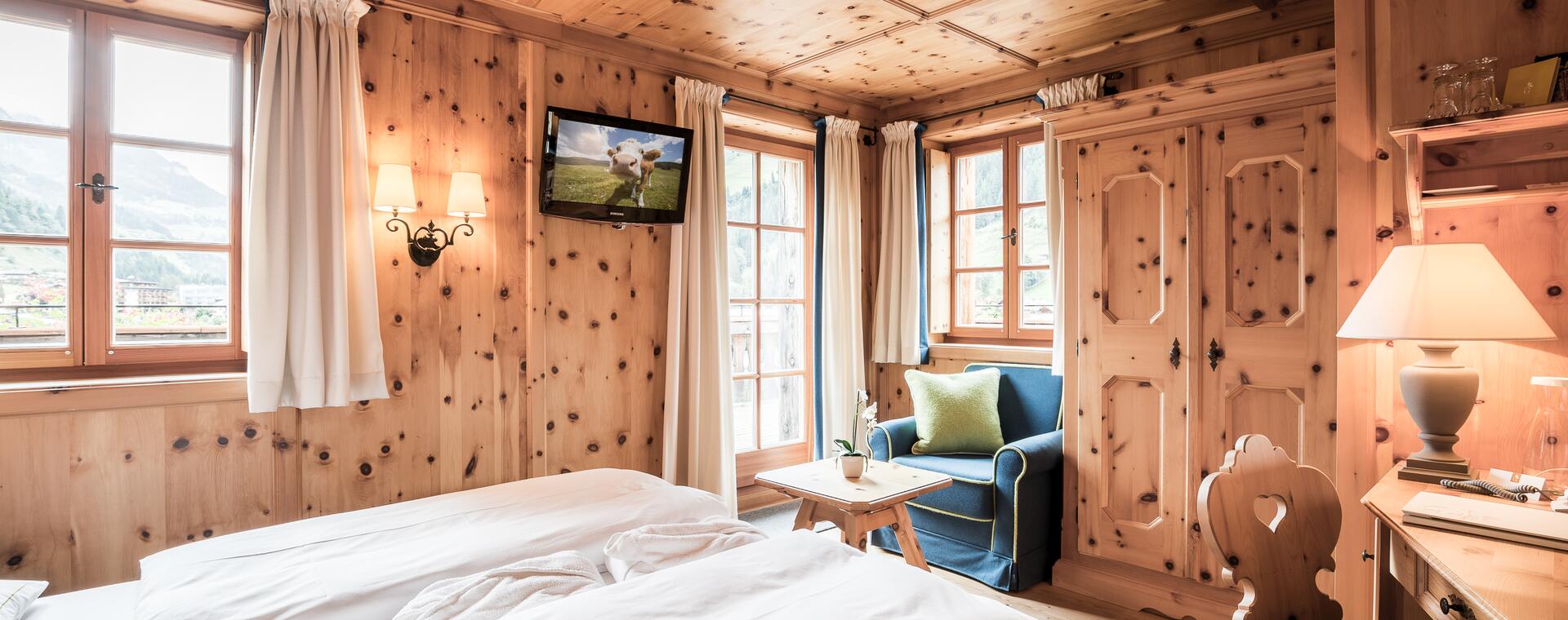 Gemütliches Zimmer im Boutique Hotel Salzburg mit Holzwänden, traditionellen Möbeln, Balkonblick und einladendem Ambiente