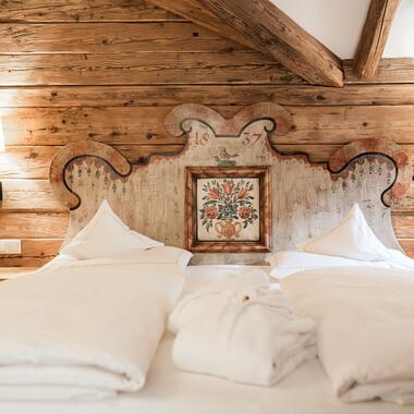 Gemütliches Doppelbett im Boutique Hotel Salzburg mit kunstvollem, traditionellem Holzkopfteil und rustikalem Charme