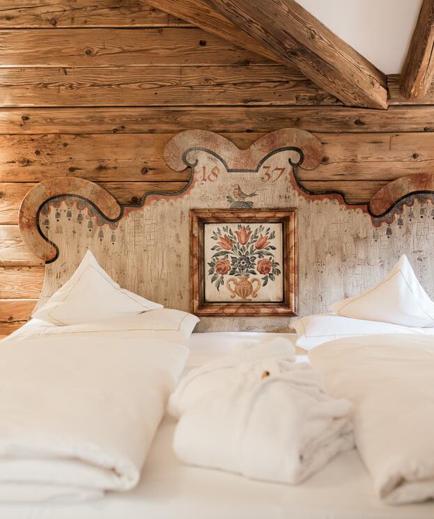 Gemütliches Doppelbett im Boutique Hotel Salzburg mit kunstvollem, traditionellem Holzkopfteil und rustikalem Charme