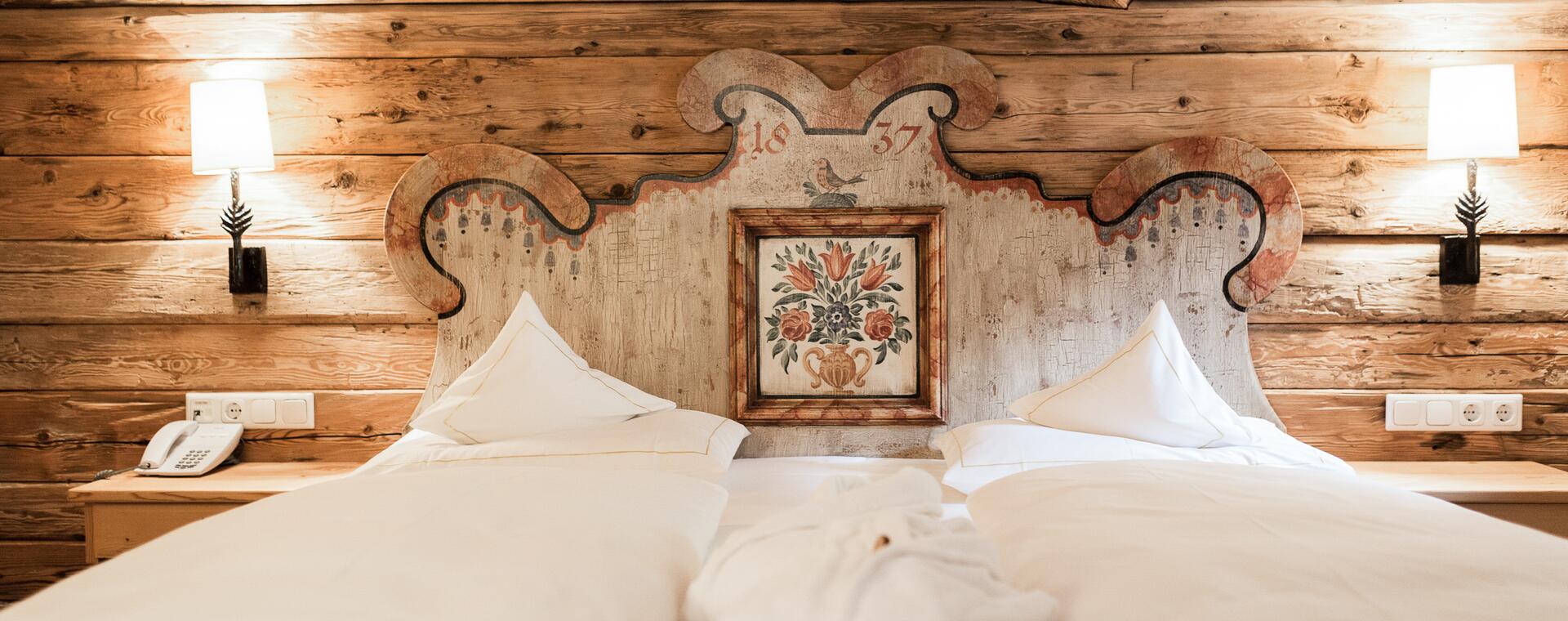 Gemütliches Doppelbett im Boutique Hotel Salzburg mit kunstvollem, traditionellem Holzkopfteil und rustikalem Charme