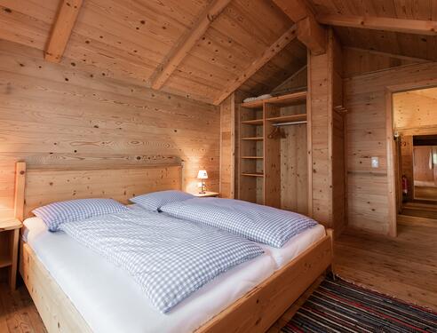 Gemütliches Schlafzimmer in einer Almhütte im Salzburger Land mit zwei Betten.