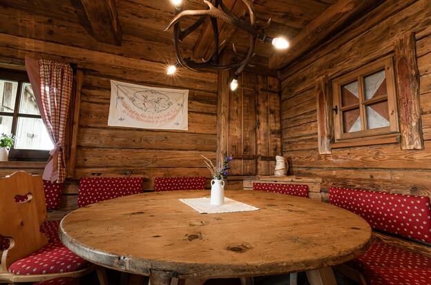 Rustikaler Tisch und Stühle in einer Alm-Hütte im Salzburger Land.