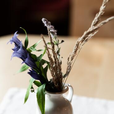 Tisch mit einer Vase voller lila Blumen in einer Almhütte im Salzburger Land