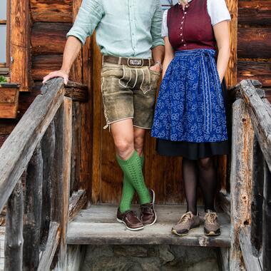 Traditionell gekleidete Gastgeber im Boutique Hotel Salzburg mit Tracht auf einer rustikalen Holztreppe