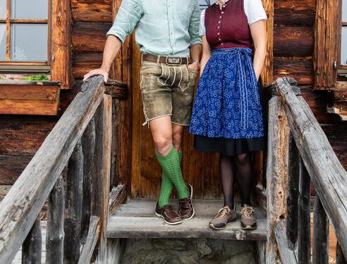 Traditionell gekleidete Gastgeber im Boutique Hotel Salzburg mit Tracht auf einer rustikalen Holztreppe