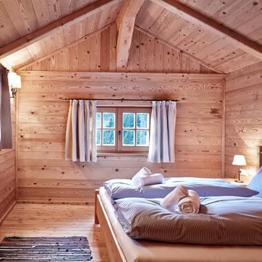 Schlafzimmer in einer Berghütte im Salzburger Land mit Holzvertäfelung und gemütlichem Bett. | © Michael Huber I www.huber-fotografie.at