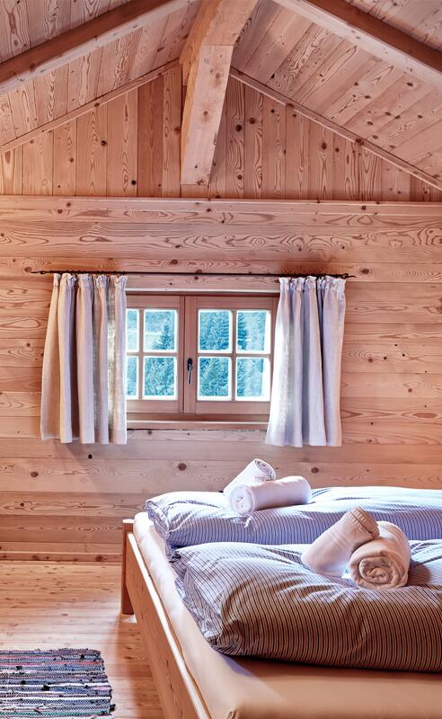 Schlafzimmer in einer Berghütte im Salzburger Land mit Holzvertäfelung und gemütlichem Bett. | © Michael Huber I www.huber-fotografie.at