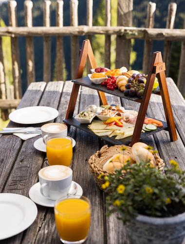 Rustikales Frühstück im Boutique Hotel Salzburg mit regionalen Spezialitäten, frischem Gebäck und Säften, auf einer Holzterrasse mit Bergblick