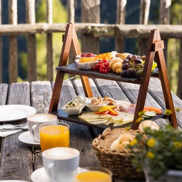 Gemütliches Frühstück auf der Terrasse einer Berghütte im Salzburger Land, umgeben von Natur.