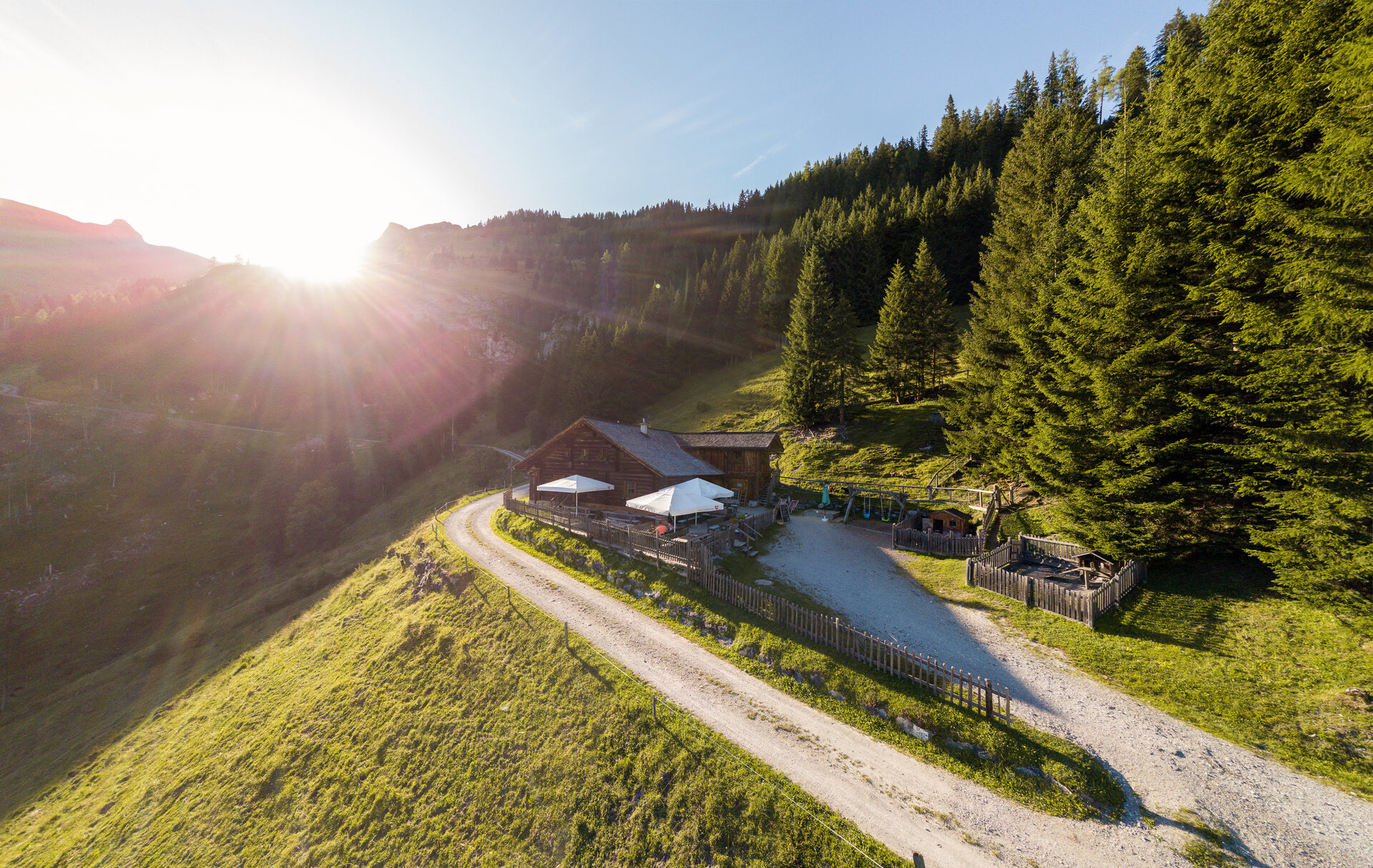 Idyllische Almhütte nahe dem Boutique Hotel Salzburg bei Sonnenaufgang, umgeben von malerischer Berglandschaft und grünen Wiesen