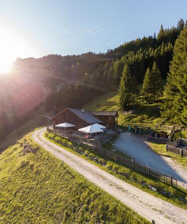 Idyllische Almhütte nahe dem Boutique Hotel Salzburg bei Sonnenaufgang, umgeben von malerischer Berglandschaft und grünen Wiesen