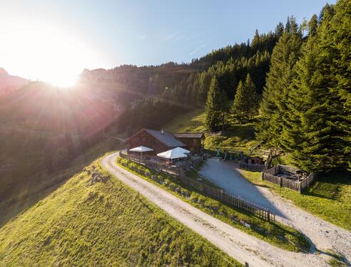 Idyllische Almhütte nahe dem Boutique Hotel Salzburg bei Sonnenaufgang, umgeben von malerischer Berglandschaft und grünen Wiesen