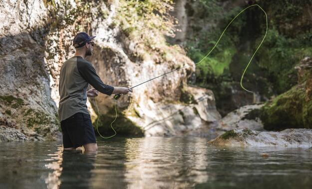 Mann steht im Wasser und wirft Angelrute aus | © Michael Groessinger