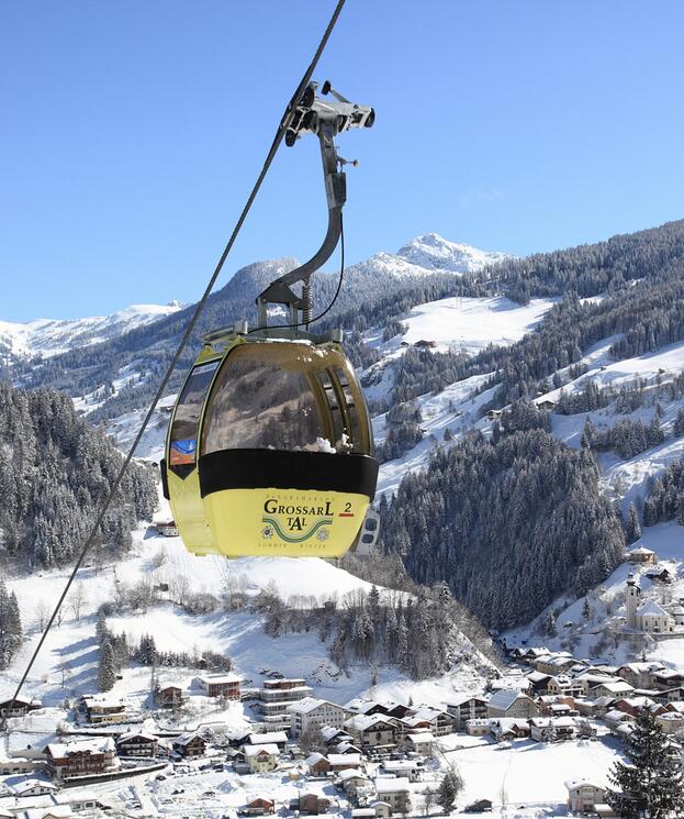 Eine Seilbahn fährt über schneebedeckte Berge und ein Dorf, während sich die winterliche Landschaft für Salzburg Winterwandern entfaltet | © www.grossarltal.info