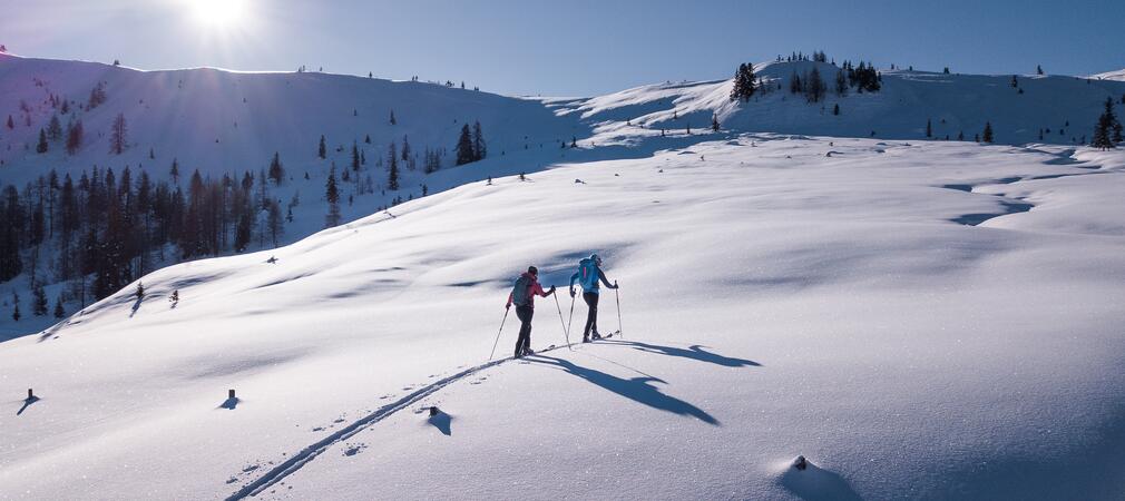 Zwei Skitourengeher in verschneiter Berglandschaft bei Sonnenschein